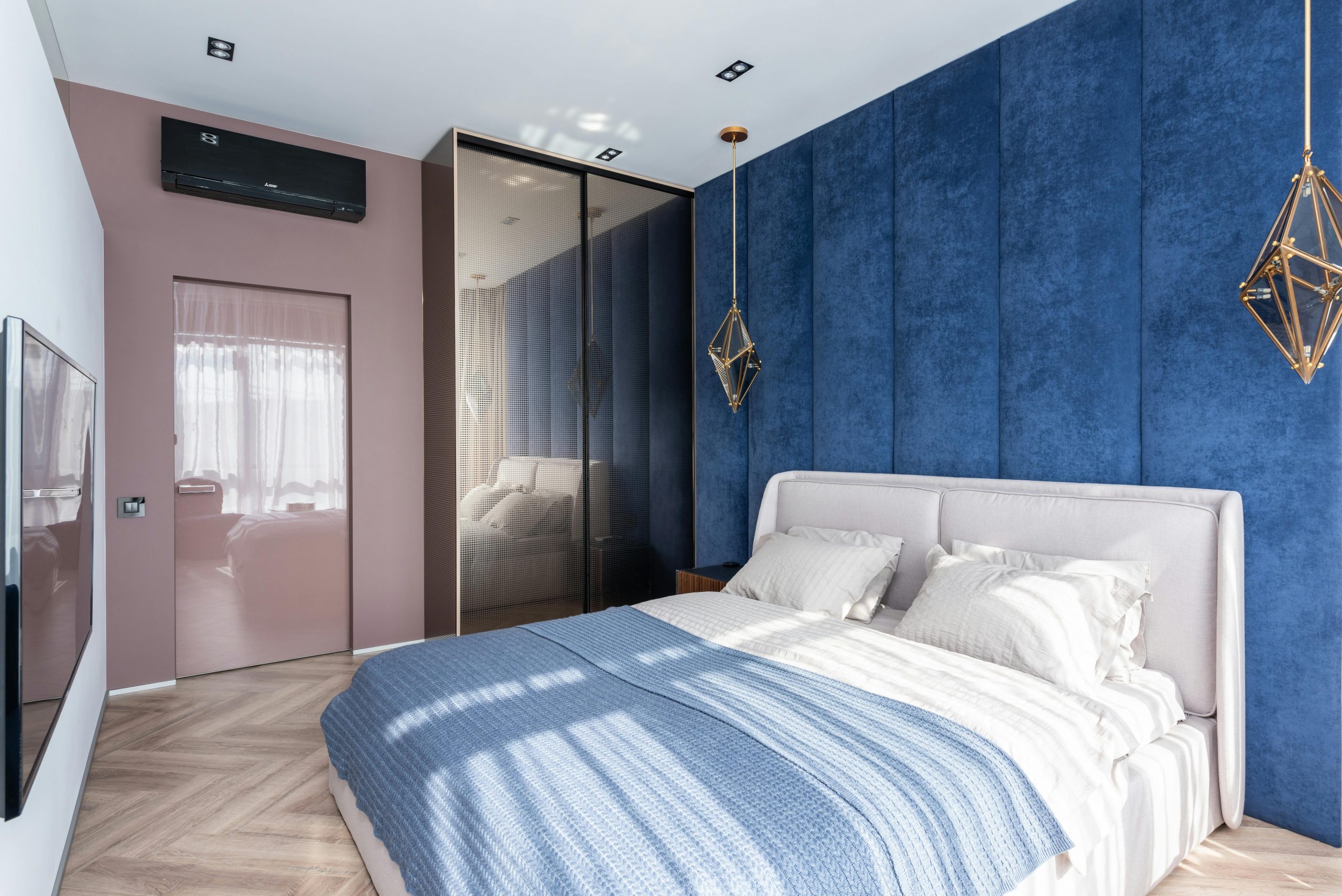 bedroom with a blue velvet accent wall and a bed dressed in blue and white linens