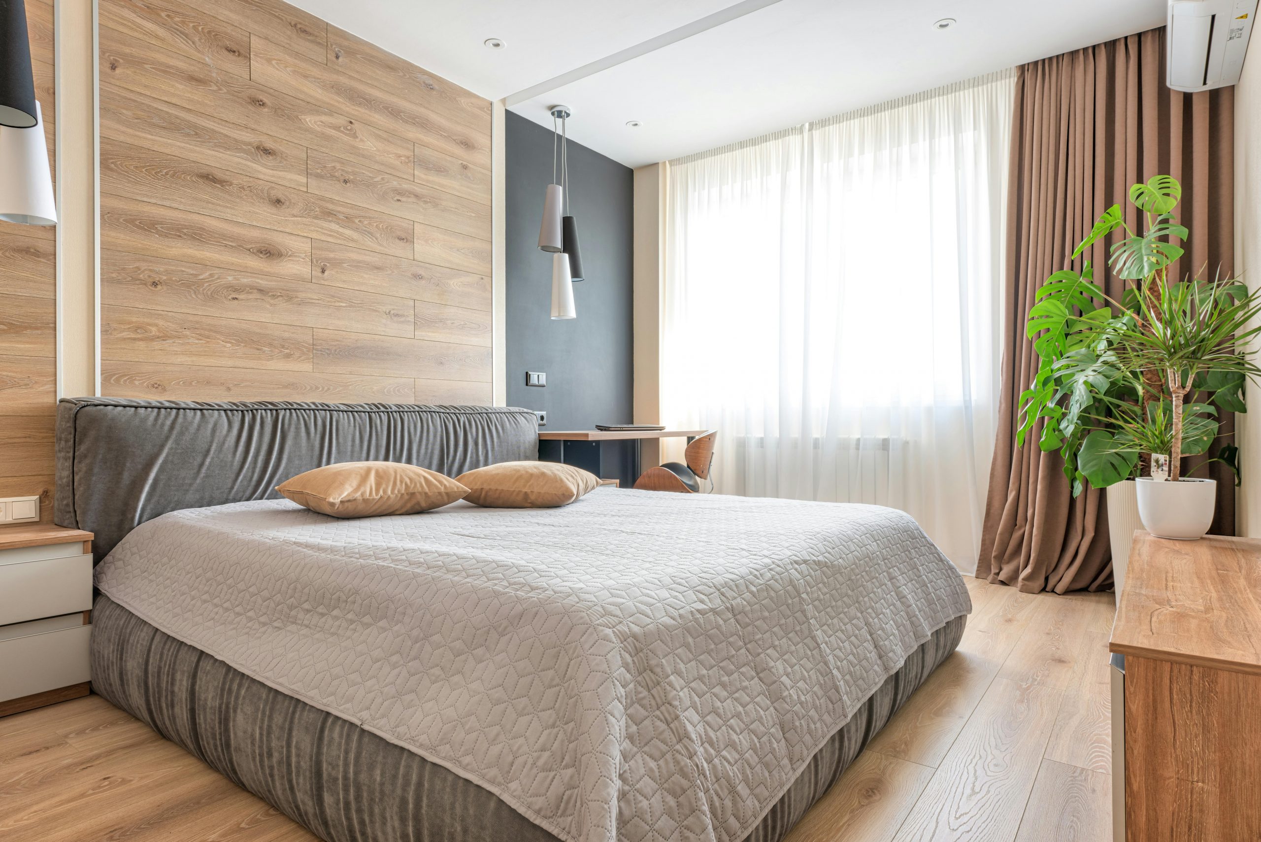 modern bedroom featuring gray walls and a warm wooden accent wall behind a white bed