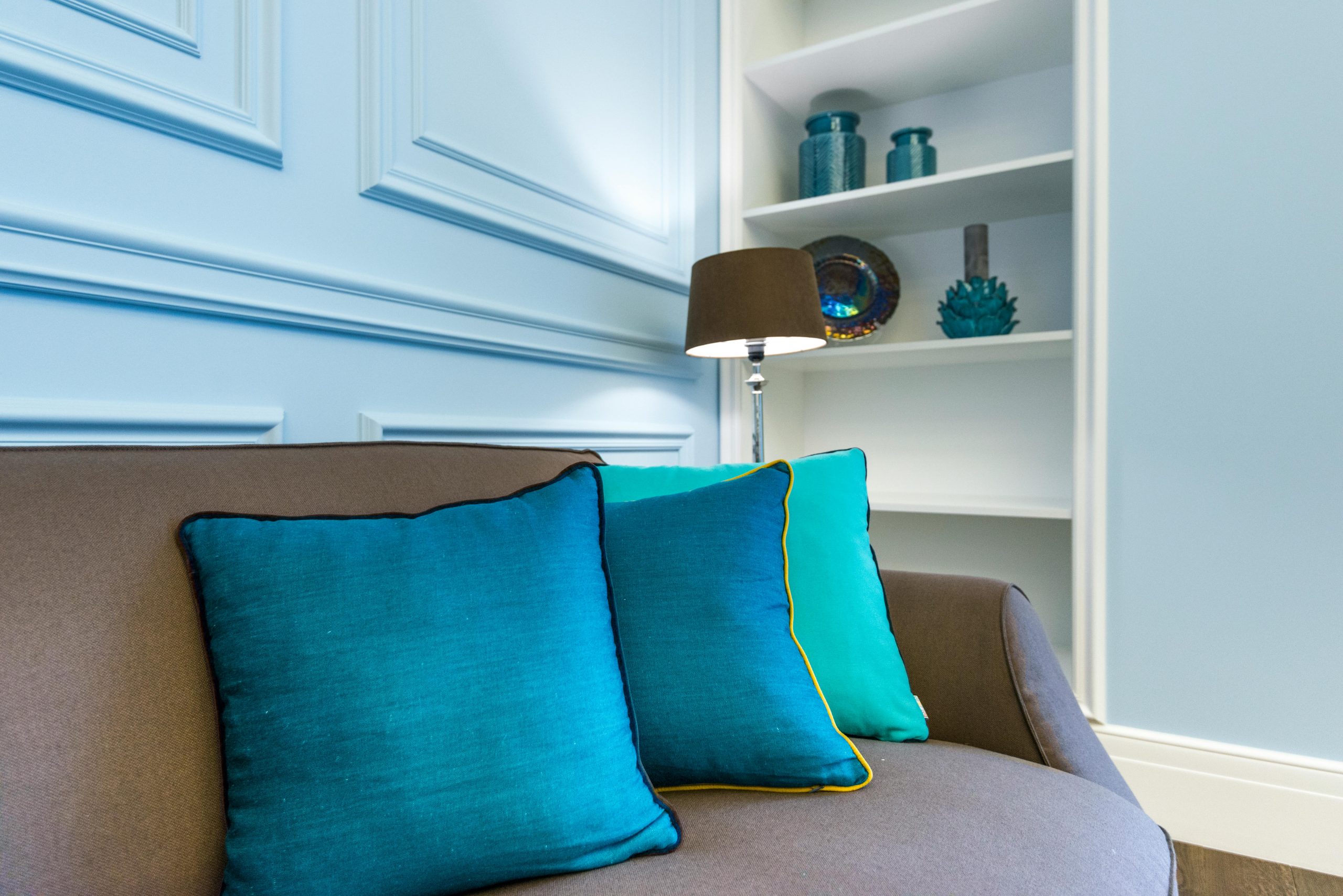 living room with a soft powder blue panel accent wall and a brown couch with throw pillows in various shades of blue